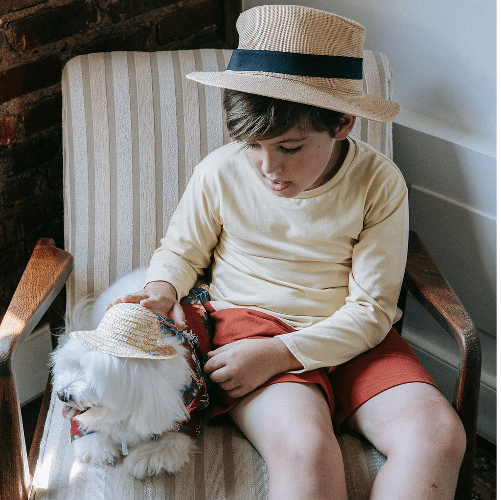 A boy sitting on a chair with a white puppy beside him