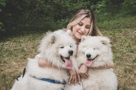 Woman smiling with two white dogs