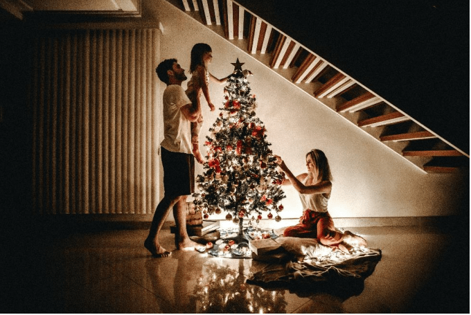 A family putting lights on a Christmas tree