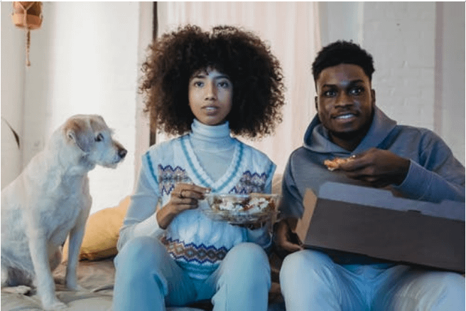 Couple watching a movie next to a curious dog