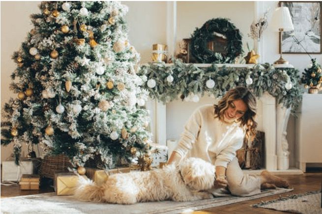 Woman cuddling with her dog in front of the Christmas tree